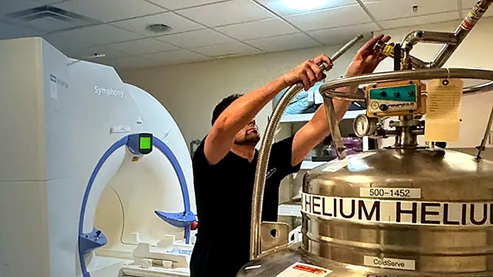 MRI helium fill in progress with a cryogenic helium dewar beside an MRI scanner during preventive cryogenic service