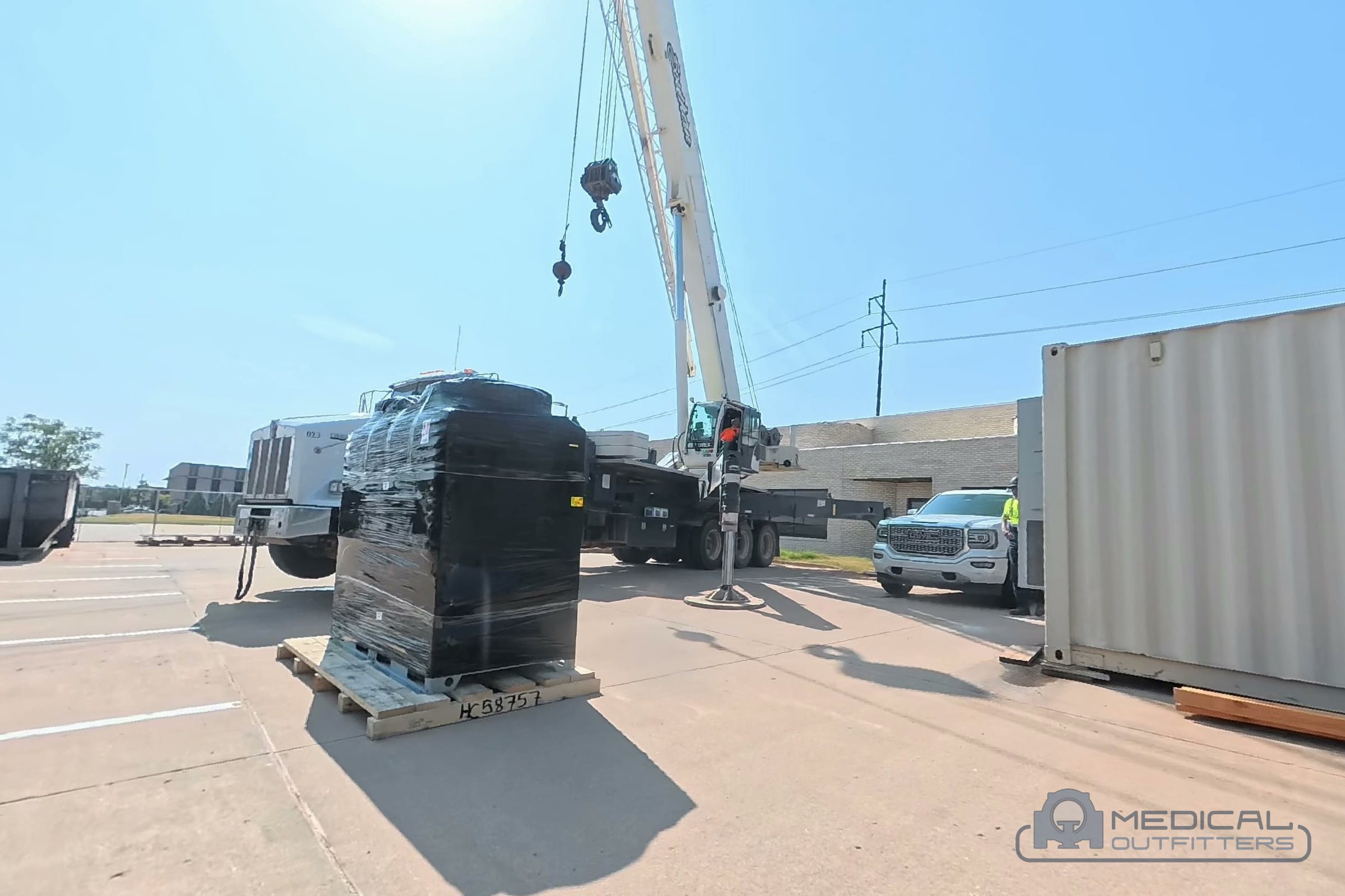 Crane, shipping container and crated CT scanner on delivery day at a Medical Outfitters installation in Oklahoma City