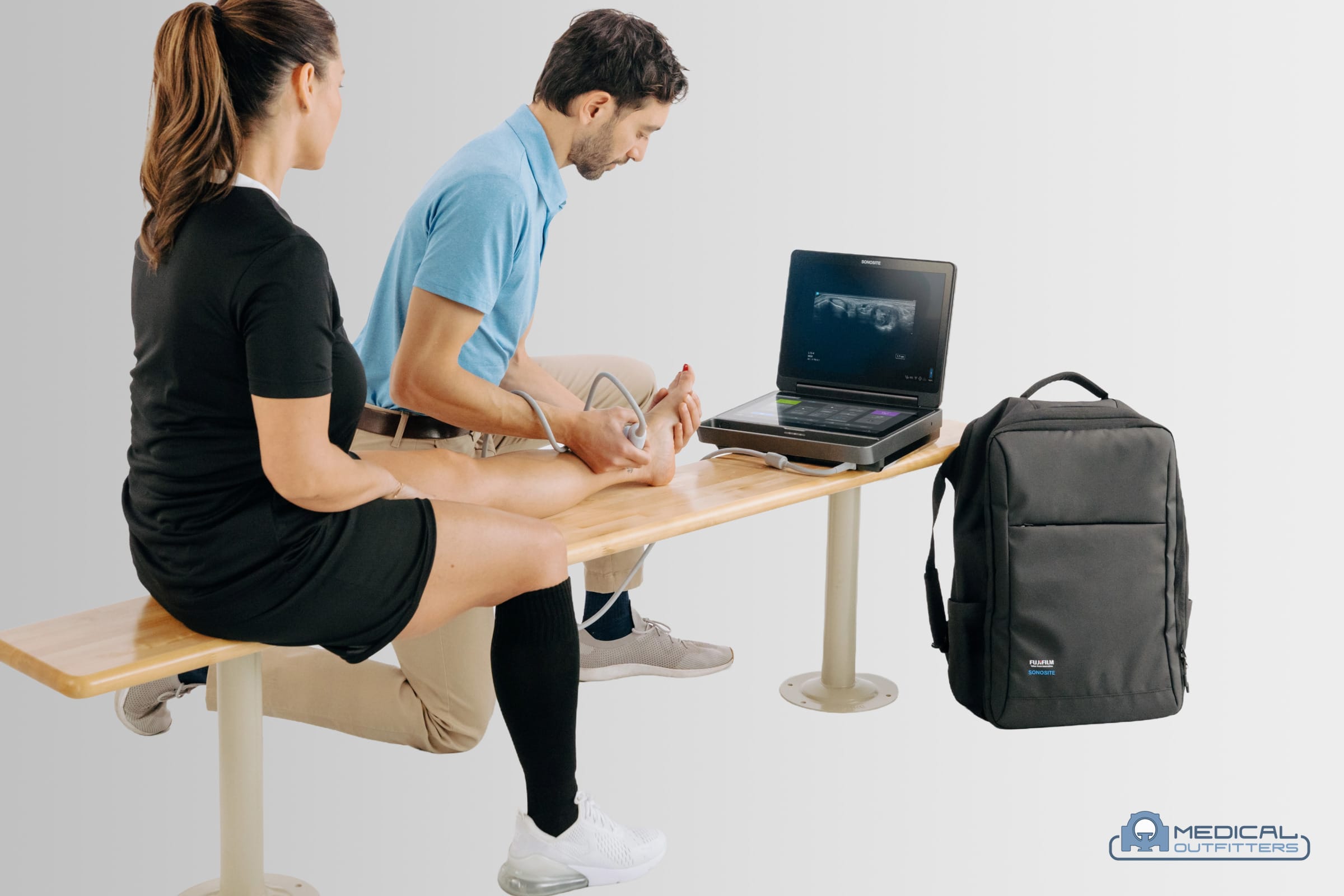 Sports medicine clinician scanning a patient's knee with a portable Fujifilm Sonosite ultrasound system and a linear probe, photo courtesy of Fujifilm Sonosite, with the Medical Outfitters watermark
