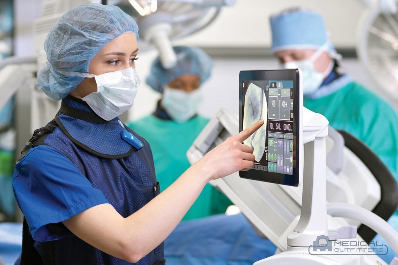 Surgical team using the touchscreen of a GE HealthCare OEC Elite CFD mobile C-arm in the operating room, photo courtesy of GE HealthCare, with the Medical Outfitters watermark