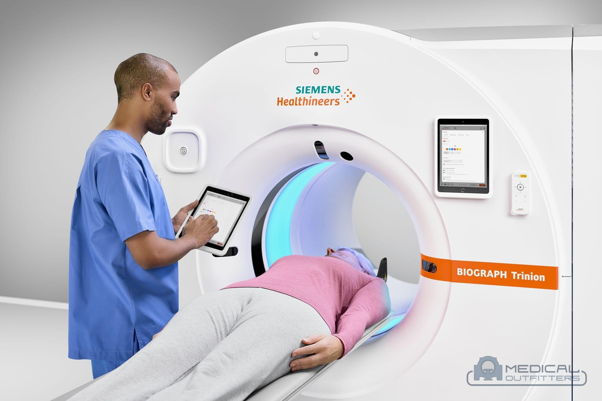 Technologist with a tablet beside a patient lying in the bore of a Siemens Biograph Trinion PET/CT scanner, photo courtesy of Siemens Healthineers