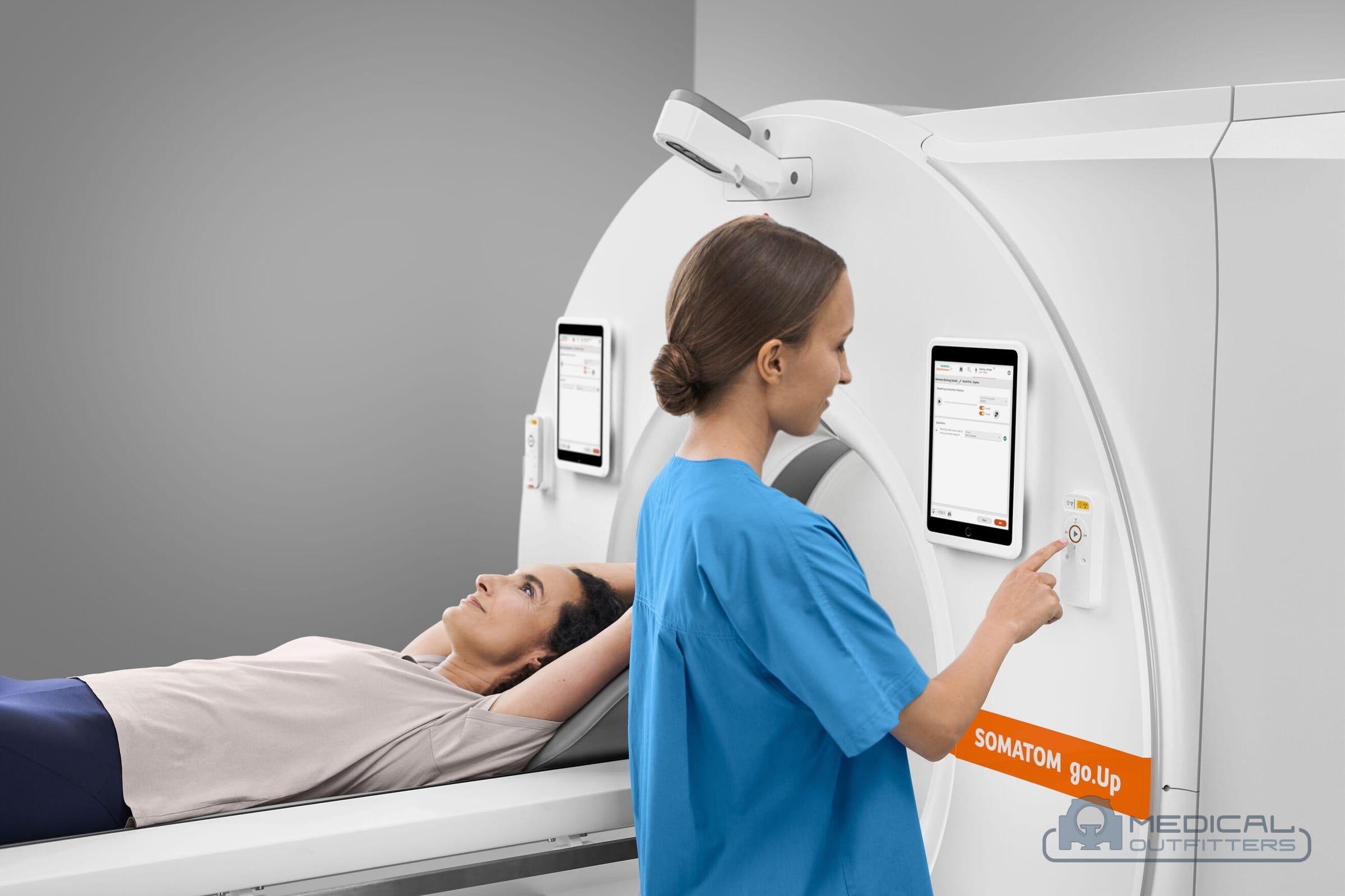 Technologist using the gantry touchscreen of a Siemens SOMATOM go.Up CT scanner while a patient lies on the table, photo courtesy of Siemens Healthineers